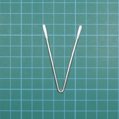 Ferramenta em forma de V com pontas brancas sobre superfície de corte verde quadriculada