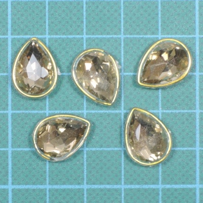 Cinco gemas em forma de gota castanhas com margem dourada sobre grelha azul