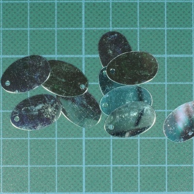 Lâminas ovais metálicas refletoras em superfície quadriculada verde