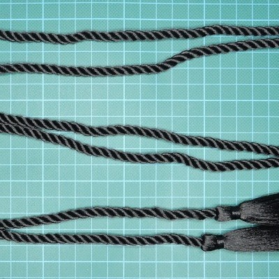 Cordão preto com franjas numa superfície verde quadriculada