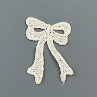 Aplique em forma de laço branco bordado sobre fundo cinzento