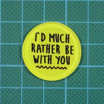 Botão amarelo redondo com texto preto colocado sobre superfície azul com linhas verdes.