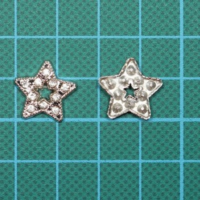 Dois botões de estrela com pedras brilhantes sobre superfície azul quadriculada