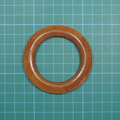 Anel de madeira castanha claro sobre fundo verde com grade azul clara