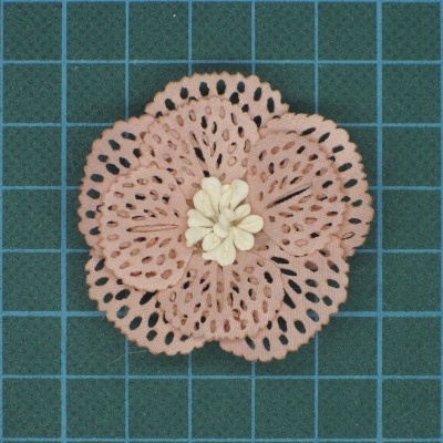 Flor rosa pastel em tecido com centro branco, sobre fundo verde de grelha.