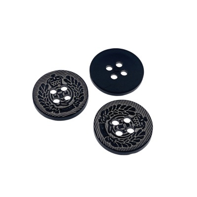Três botões pretos com quatro furos, dois com relevo e coroa, um liso, sobre fundo branco.