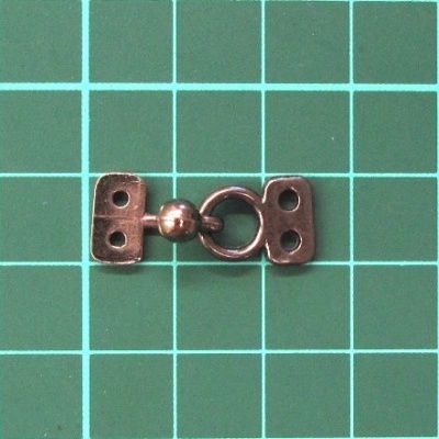 Fecho metálico bronze sobre superfície verde quadriculada