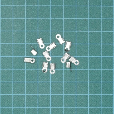 Terminais elétricos metálicos prateados sobre superfície verde com grelha branca