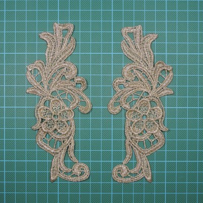 Dois apliques de renda bege com padrão floral sobre superfície de corte verde