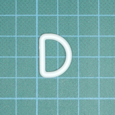 Anel em forma de D plástico branco sobre fundo quadriculado verde.