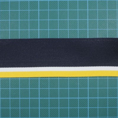 Faixa de tecido azul, branco e amarelo sobre superfície verde quadriculada