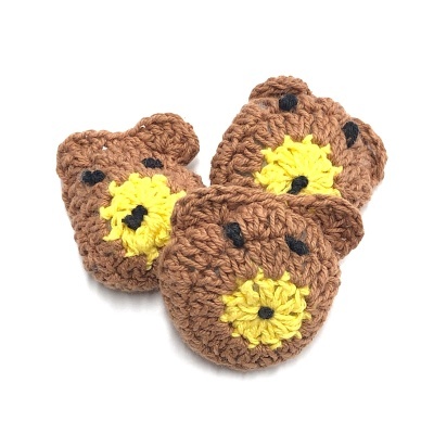 Três ursinhos de croché castanhos com detalhes amarelos e pretos