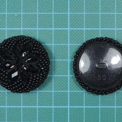 Dois botões pretos redondos sobre superfície quadriculada verde