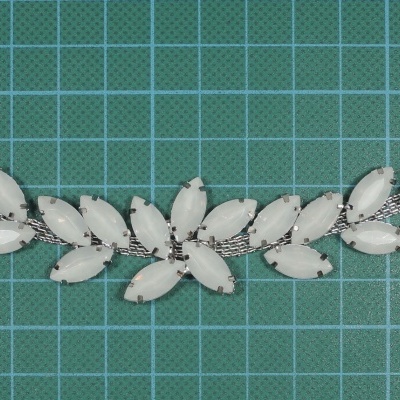 Pulseira feminina com pedras brancas e fecho de metal prateado sobre fundo quadriculado verde