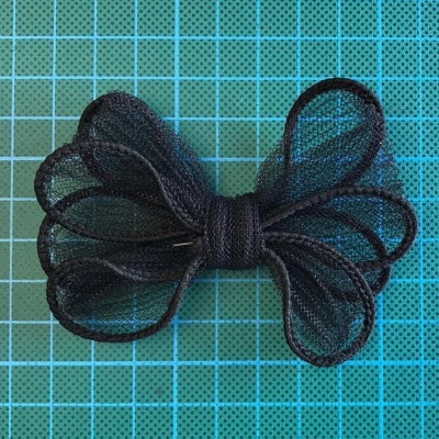 Laço preto de tecido tipo tule sobre fundo quadriculado azul