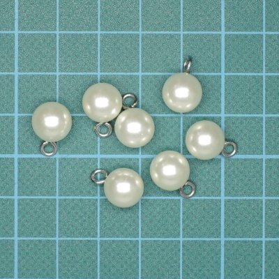 Pendurados de pérolas falsas com argolas metálicas sobre fundo verde quadriculado