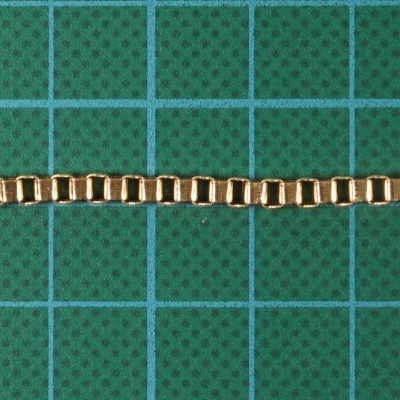 Corrente dourada sobre superfície verde com quadrícula azul
