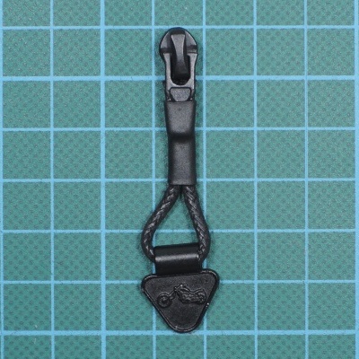 Puxador de zíper preto com corda trançada e base triangular em tecido verde quadriculado