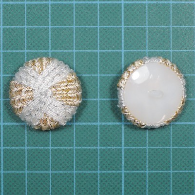 Dois botões redondos com superfície têxtil e branca lisa sobre fundo de grade verde