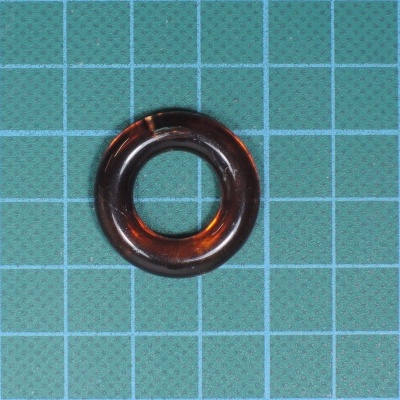 Anel circular castanho translúcido sobre superfície azul com grelha branca