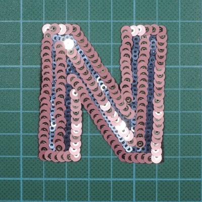 Aplicação de lantejoulas letra N em tecido quadriculado verde