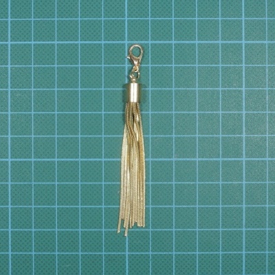 Chaveiro tassel dourado sobre fundo quadriculado azul e verde