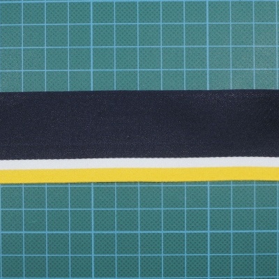 Tira têxtil preta com riscas branca e amarela sobre fundo verde quadriculado