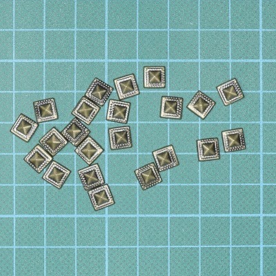 Pequenas tachas metálicas quadradas sobre superfície azul quadriculada