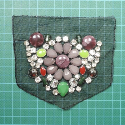 Aplicação decorativa com pedras coloridas sobre tecido de rede preta