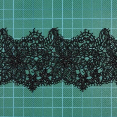 Renda preta com padrão floral detalhado sobre fundo verde quadriculado