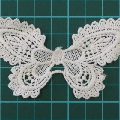 Aplicação de renda branca em forma de borboleta em fundo quadriculado verde