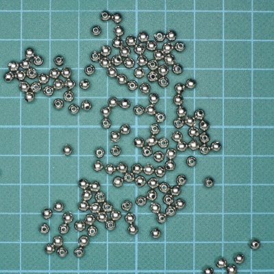 Contas metálicas prateadas sobre superfície verde com grade azul