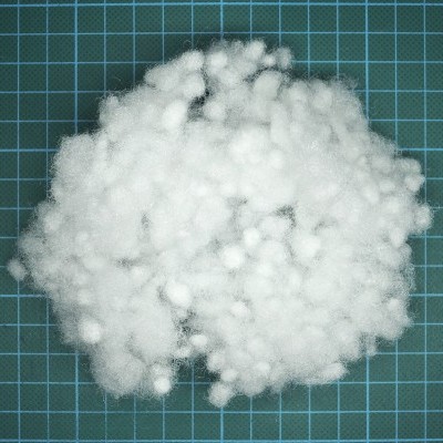 Flocos de enchimento sintético branco sobre superfície quadriculada azul