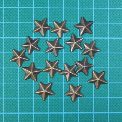Tachas decorativas em forma de estrela com acabamento metálico bronze sobre superfície quadriculada azul