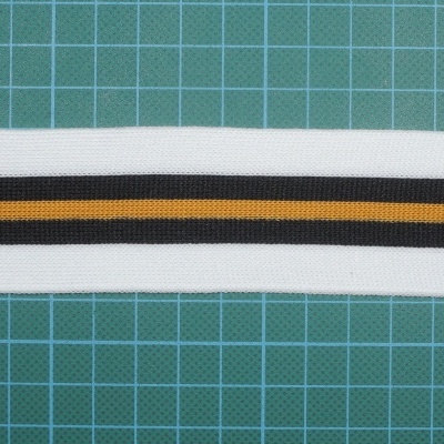 Faixa elástica branca com riscas preta e laranja sobre fundo quadriculado verde