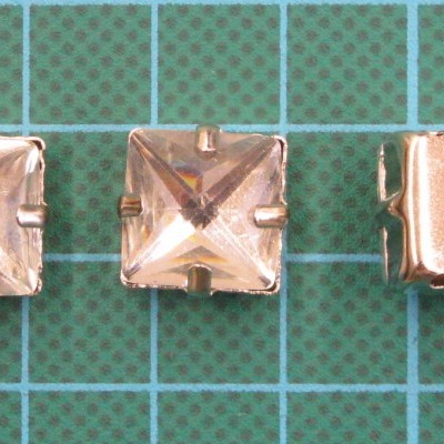 Três botões quadrados transparentes com base metálica dourada sobre fundo verde quadriculado