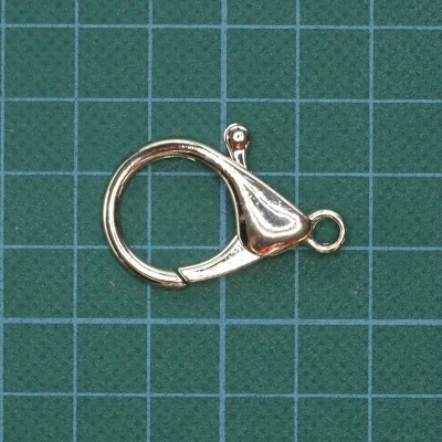 Fecho metálico dourado sobre superfície verde quadriculada