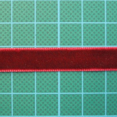 Fita de veludo vermelha sobre superfície verde com grelha.