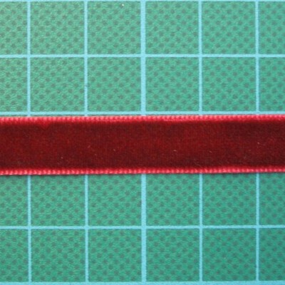 Fita de veludo vermelha sobre superfície verde com grade azul clara