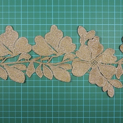 Fita decorativa dourada com padrão de folhas sobre fundo verde quadriculado