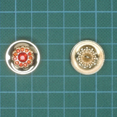 Dois botões decorativos metálicos sobre superfície quadriculada verde