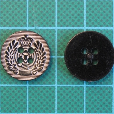 Dois botões redondos, um metálico com relevo e outro preto liso, sobre superfície de grade verde