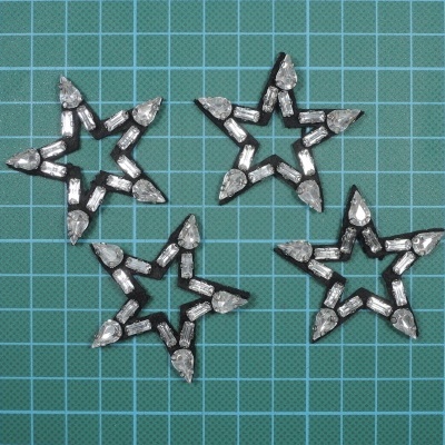 Quatro estrelas de metal prateado com base preta sobre superfície azul quadriculada