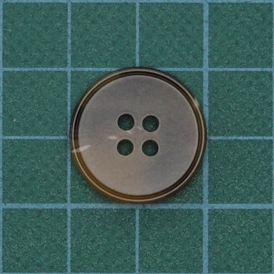 Botão redondo bege com quatro furos sobre fundo verde quadriculado