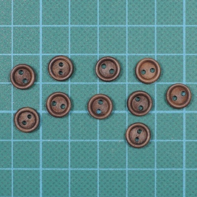 Botões castanhos redondos com dois furos em superfície verde quadriculada