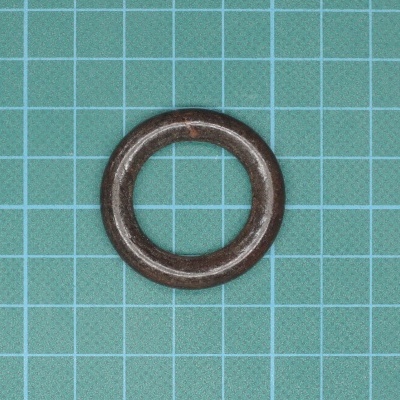 Anel de metal castanho escuro sobre fundo azul quadriculado