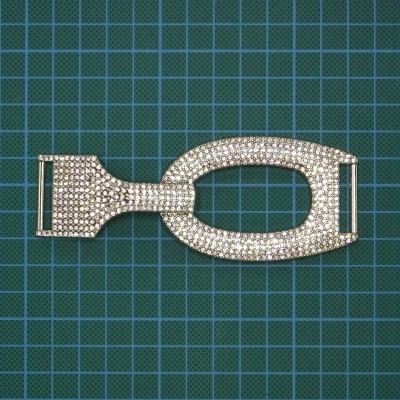 Fecho metálico prateado com cristais sobre base de corte verde