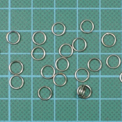 Argolas metálicas pequenas sobre superfície verde com grade branca