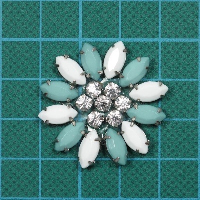 Broche floral com pedras ovais azul e brancas e pedras redondas transparentes no centro