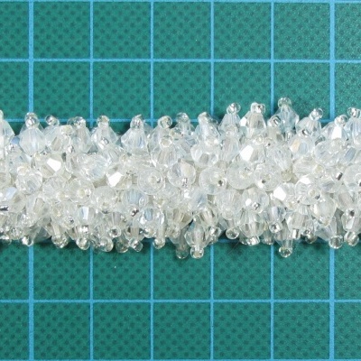 Presilha para cabelo com pedras brancas transparentes sobre fundo verde em quadrícula